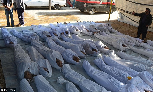 Slaughter: Syrian activists inspect the bodies of people they say were killed by nerve gas in Damascus 