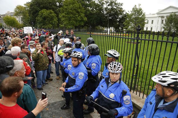 Law enforcement officers clash with protesters from the "Million Vet March on the Memorials", rallying against the closure of the U.S. National World War Two Memorial due to the current U.S. government shutdown, as they climb the fence in front of the White House gates in Washington, October 13, 2013. REUTERS/Jonathan Ernst