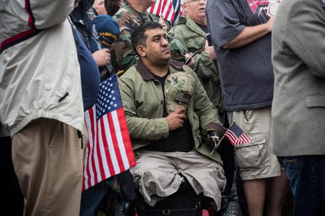 A man in a wheel chair recites the Pledge of Allegiance at a rally centered around reopening national memorials closed by the government shutdown. 