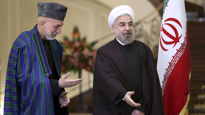 Iran's President Hassan Rouhani, right, stands with Afghan President Hamid Karzai, before their meeting at Tehran's Saadabad Palace in Iran, Sunday, Dec. 8, 2013. Karzai arrived in Tehran for a one-day visit on Sunday to discuss regional and international issues with Iranian officials. (AP Photo/Ebrahim Noroozi)