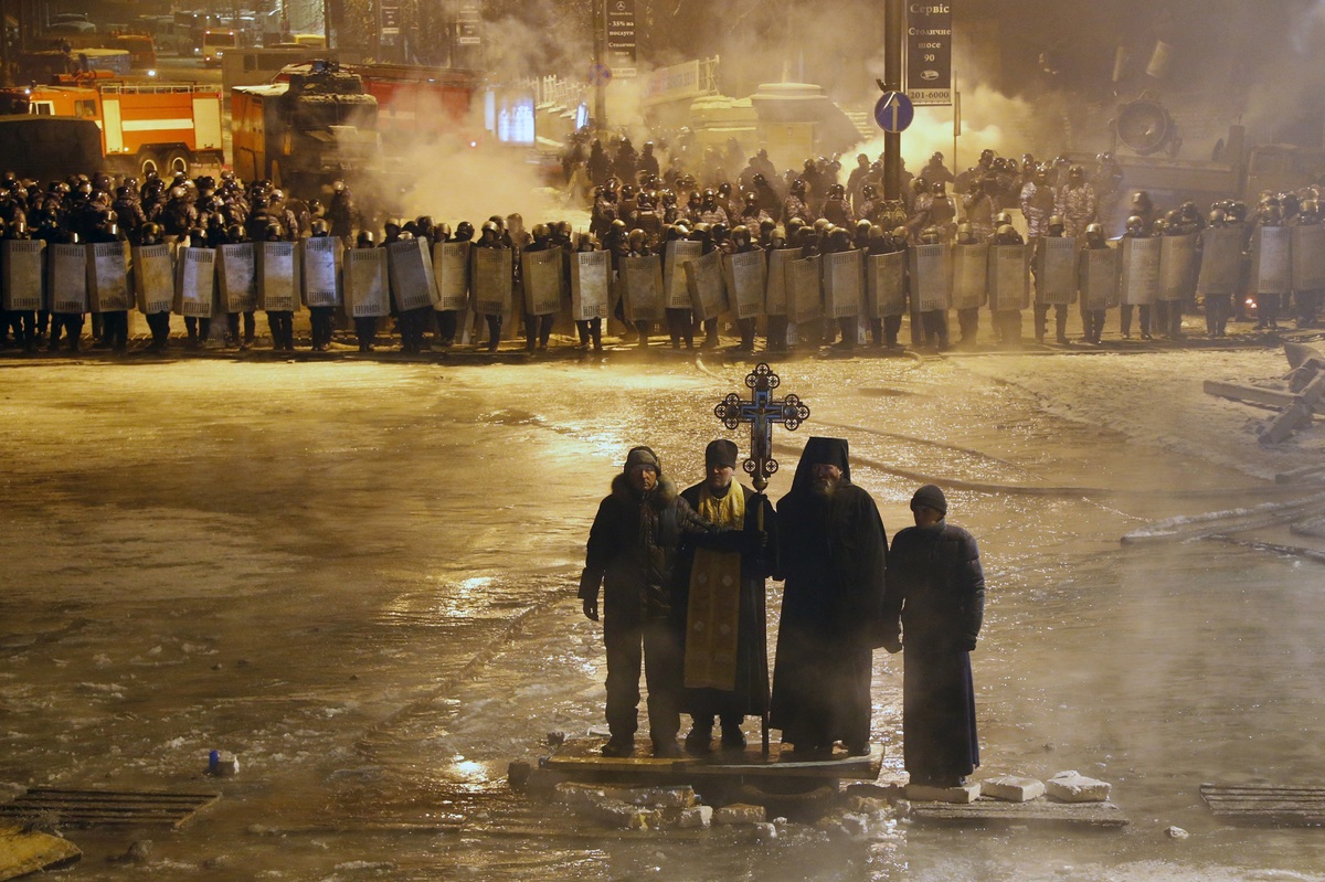 In this file photo taken on Friday, Jan. 24, 2014, Orthodox priests pray as they stand between pro-European Union activists and police lines in central Kiev, Ukraine. (AP Photo/Sergei Grits, file)